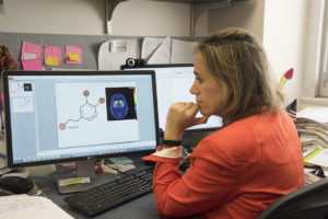 M Yanina Pepino, PhD, examines a PET image and an illustration depicting the relationship between sweets and dopamine receptors in the brain.