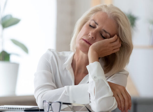 A woman sitting at a desk nods to sleep