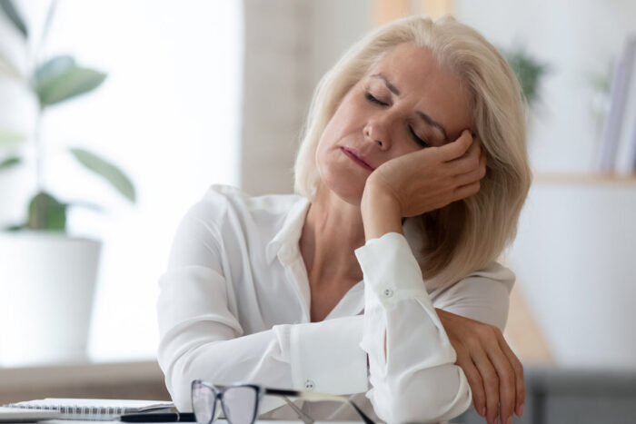A woman sitting at a desk nods to sleep