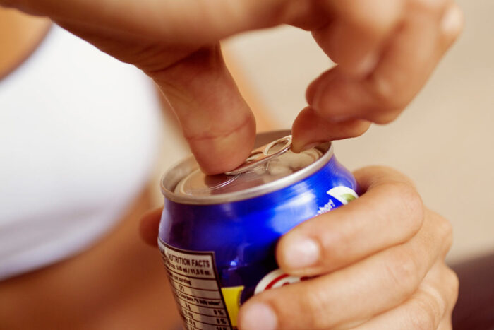 A person opens a can of a soft drink