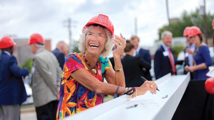 Carol B. Loeb and university leaders and guests sign the final steel beam of the Neuroscience Research Building under construction on the medical campus before the beam was placed on top of the structure.