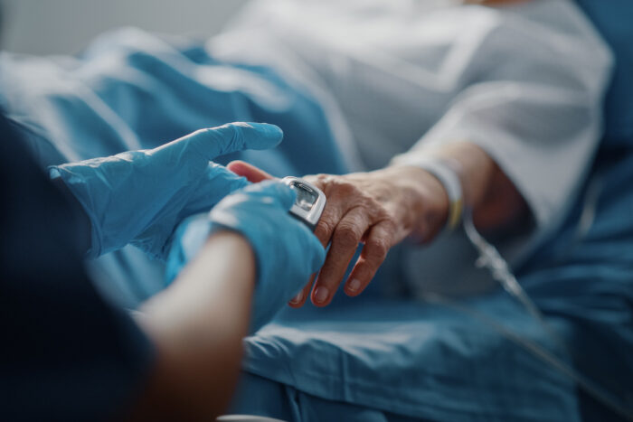 Patient with oximeter lying in a hospital bed