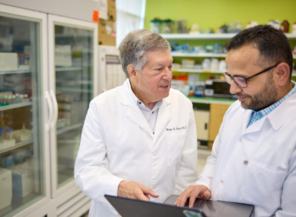 Two researchers discuss data on a laptop in the lab