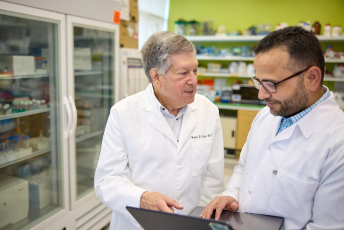 Two researchers discuss data on a laptop in the lab