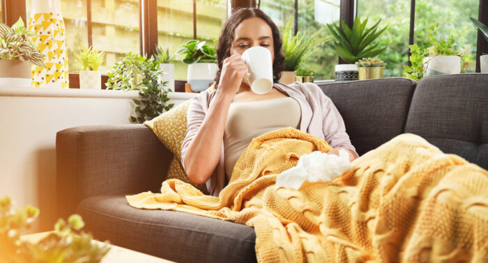 A young woman lying on her couch, drinking tea