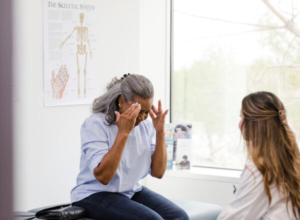 Woman explains headache symptoms to doctor