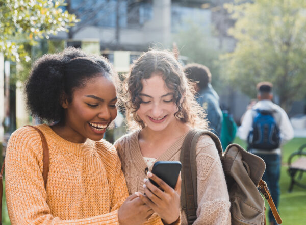 Two young women look at a smartphone together