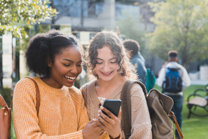 Two young women look at a smartphone together