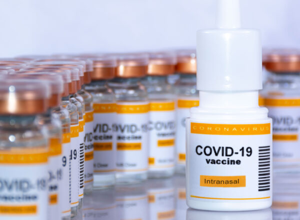 A vial of an inhalable COVID-19 vaccine sits in the foreground, with many vials of vaccine in the background.