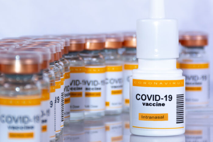 A vial of an inhalable COVID-19 vaccine sits in the foreground, with many vials of vaccine in the background.