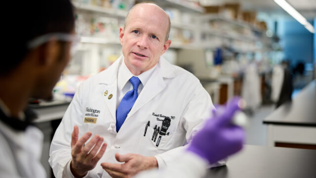 Randall J. Bateman, MD, speaking with a colleague in the lab