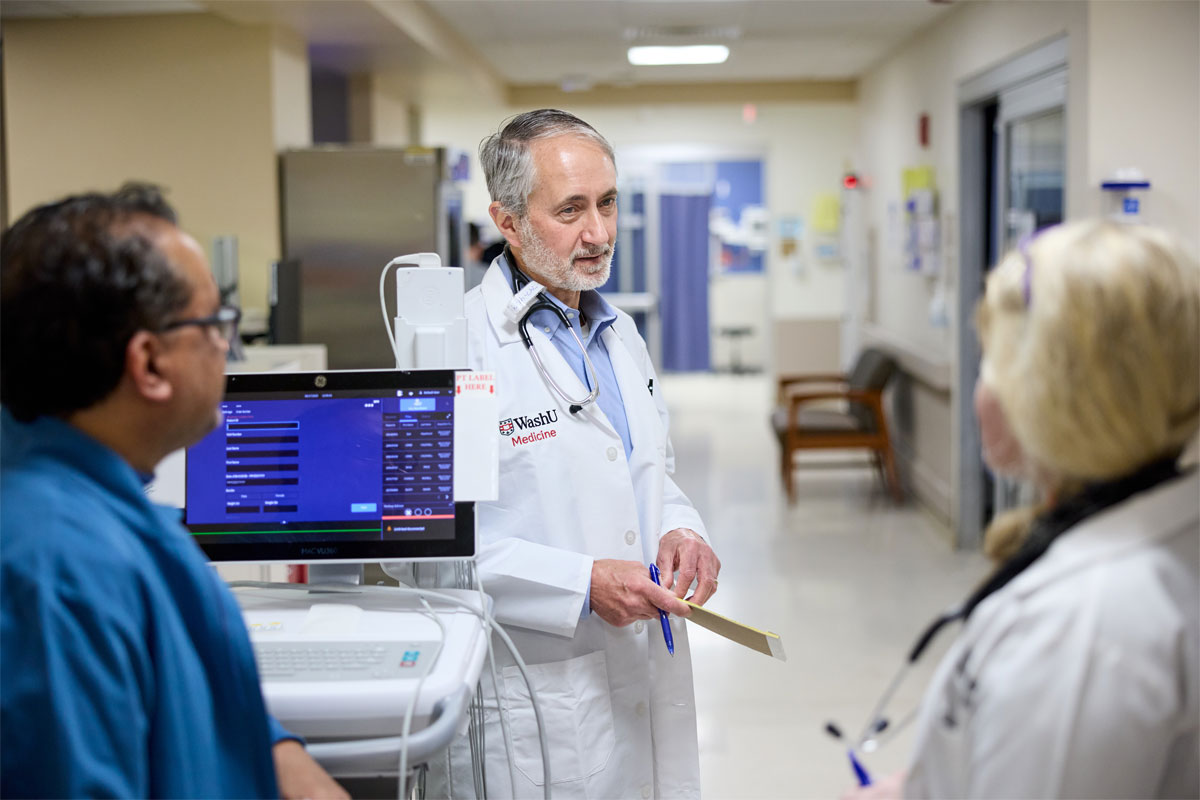 Three people talking in hallway.