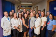 Doctors and other clinical staff posing for photo in hospital hallway