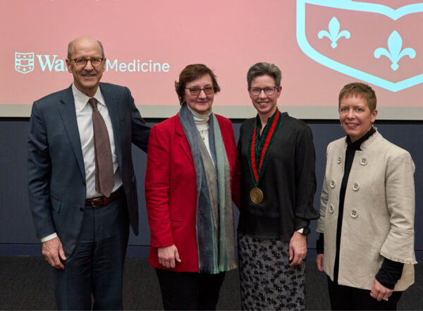One man and four women posing in front of WashU Medicine backdrop.