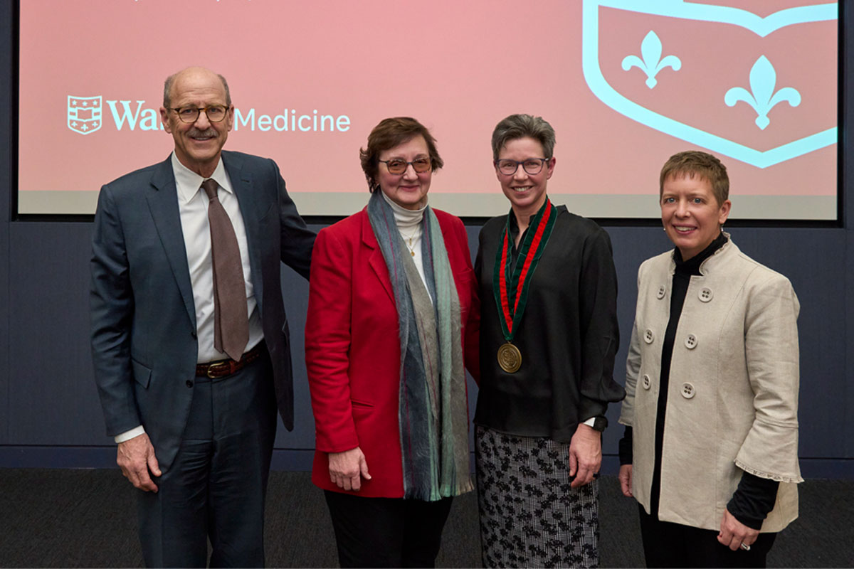 One man and four women posing in front of WashU Medicine backdrop.