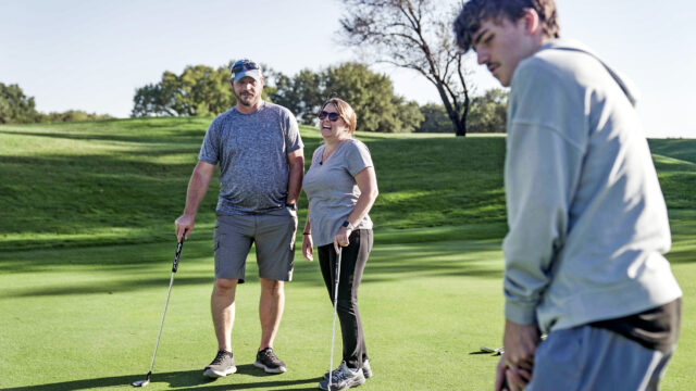Rickey Malloy who receives tofersen treatment for SOD1-ALS at WashU Medicine, plays a round of golf with his wife, Jenny, and their son, Kash.