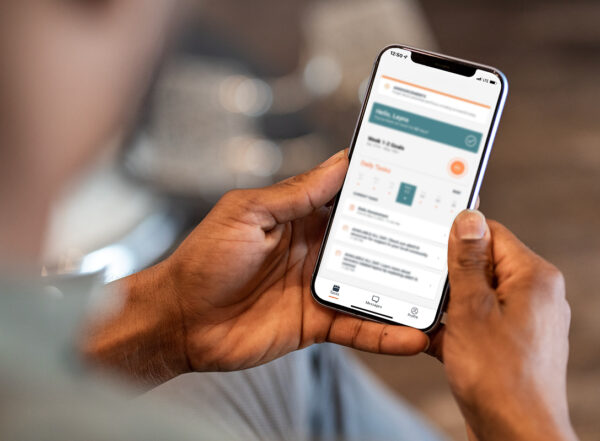 Hands holding a smart phone with an app open and text blurred