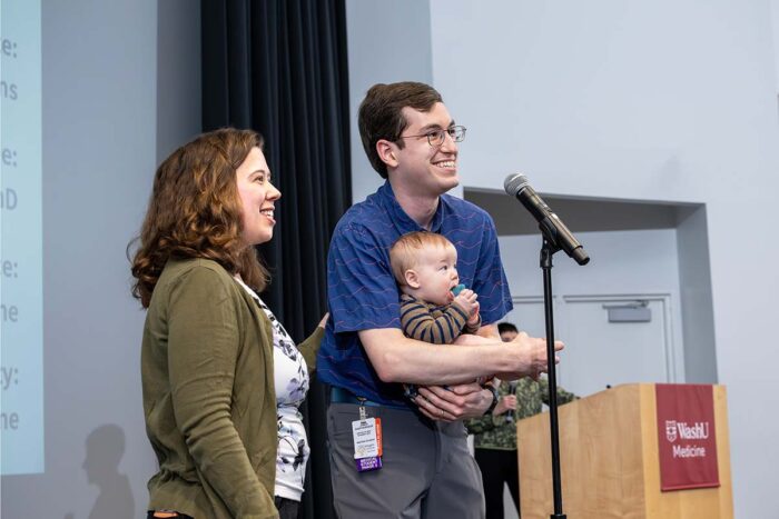 Couple stands on stage, holding baby
