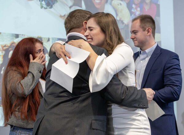 Woman in white dress hugs father on stage during Match Day 2026
