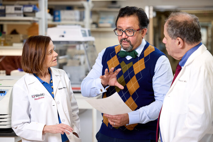 three scientists talking in a lab