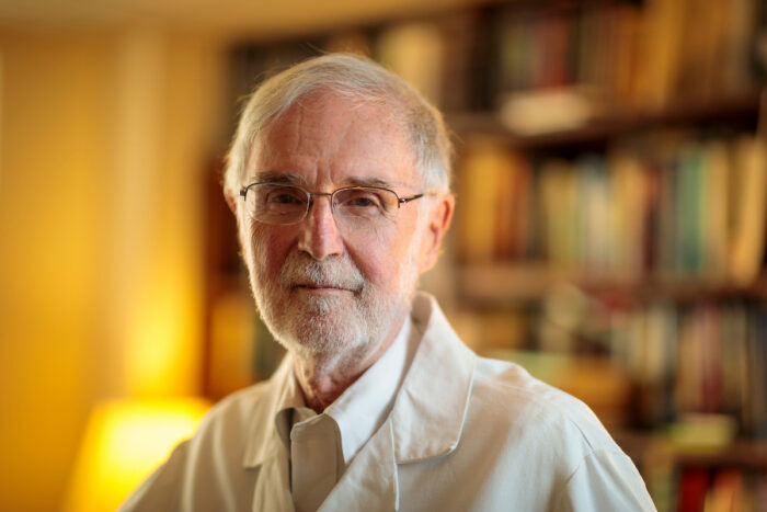 Marcus E. Raichle, wearing a tie and white coat, looks to the camera.