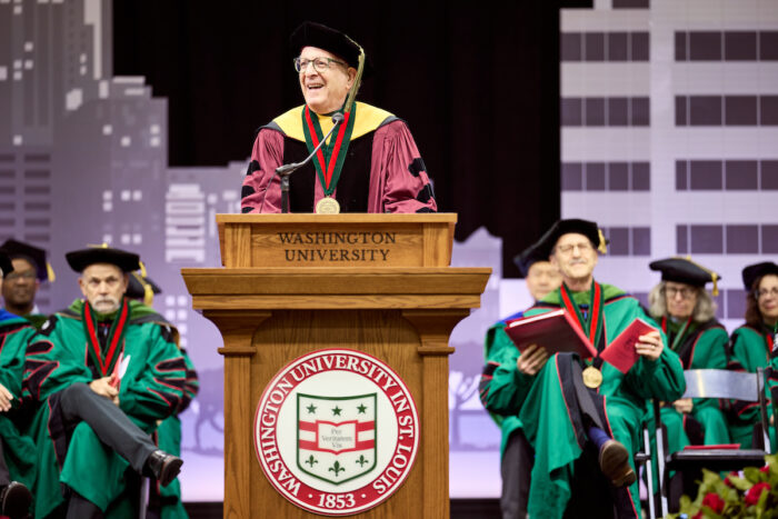Jeffrey Gordon, MD, dressed in Commencement regalia, stands at the podium to address the WashU Medicine Graduating Class of 2026. 
