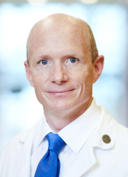Headshot of male physician/innovator who is smiling and wearing a white coat