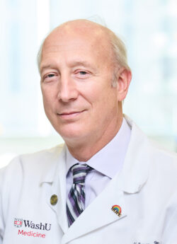 Headshot of male physician/innovator who is smiling and wearing a white coat