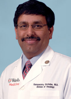 Headshot of male physician who is smiling and wearing glasses and a white coat