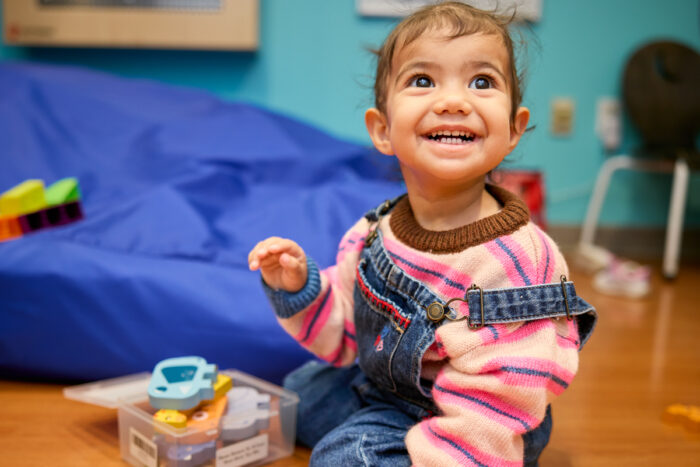 smiling, happy child playing on the floor, looking upwards